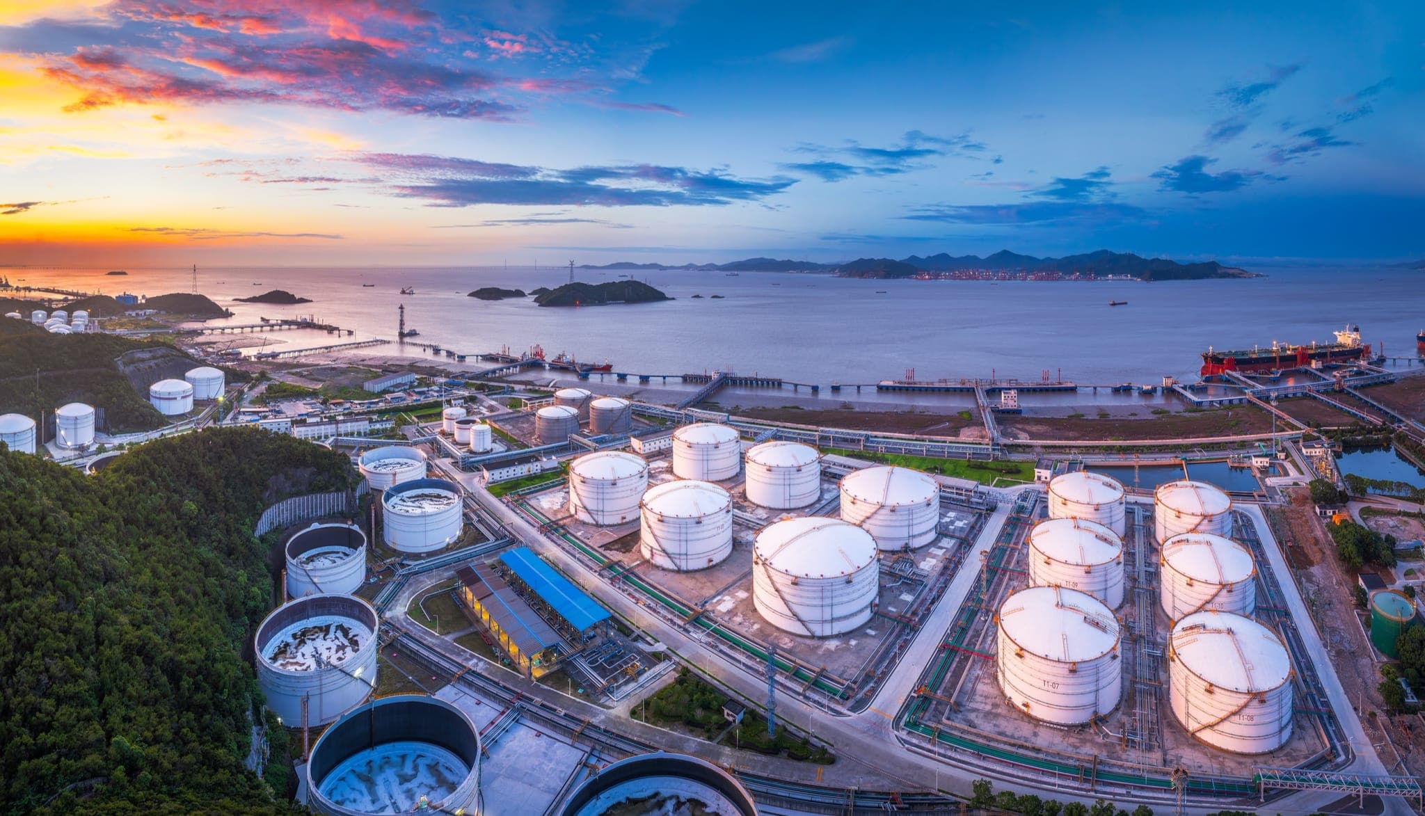 Coastal oil and gas terminal with storage tanks at dusk