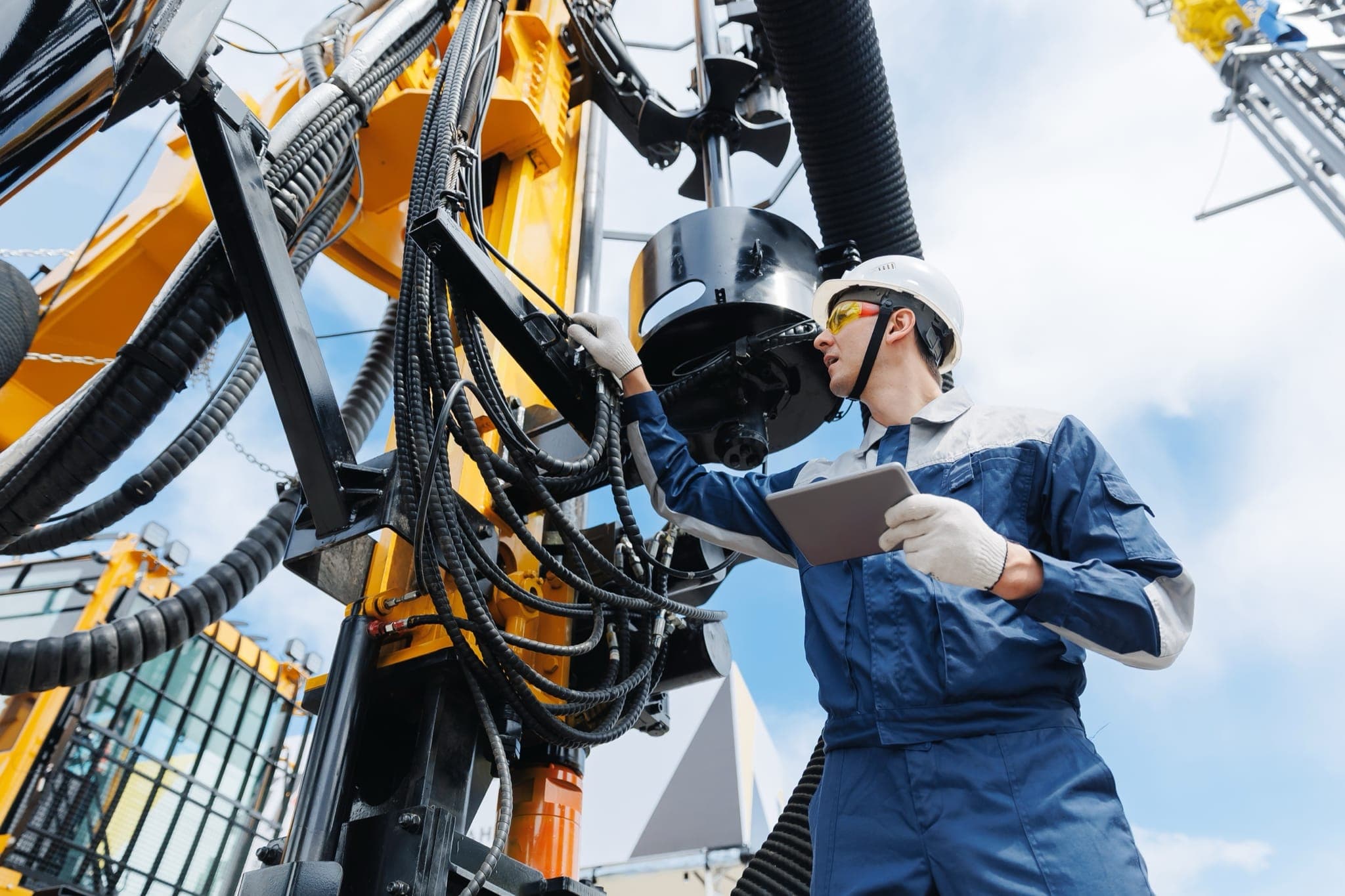 Drilling rig technician inspecting hydraulic hose assembly