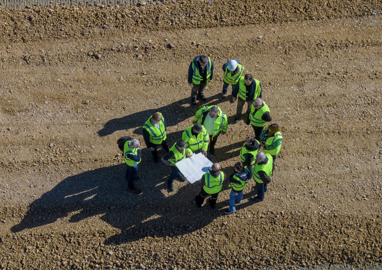 Aerial view of a Klarwin consultancy session on a landfill site — engineers reviewing technical drawings on-site