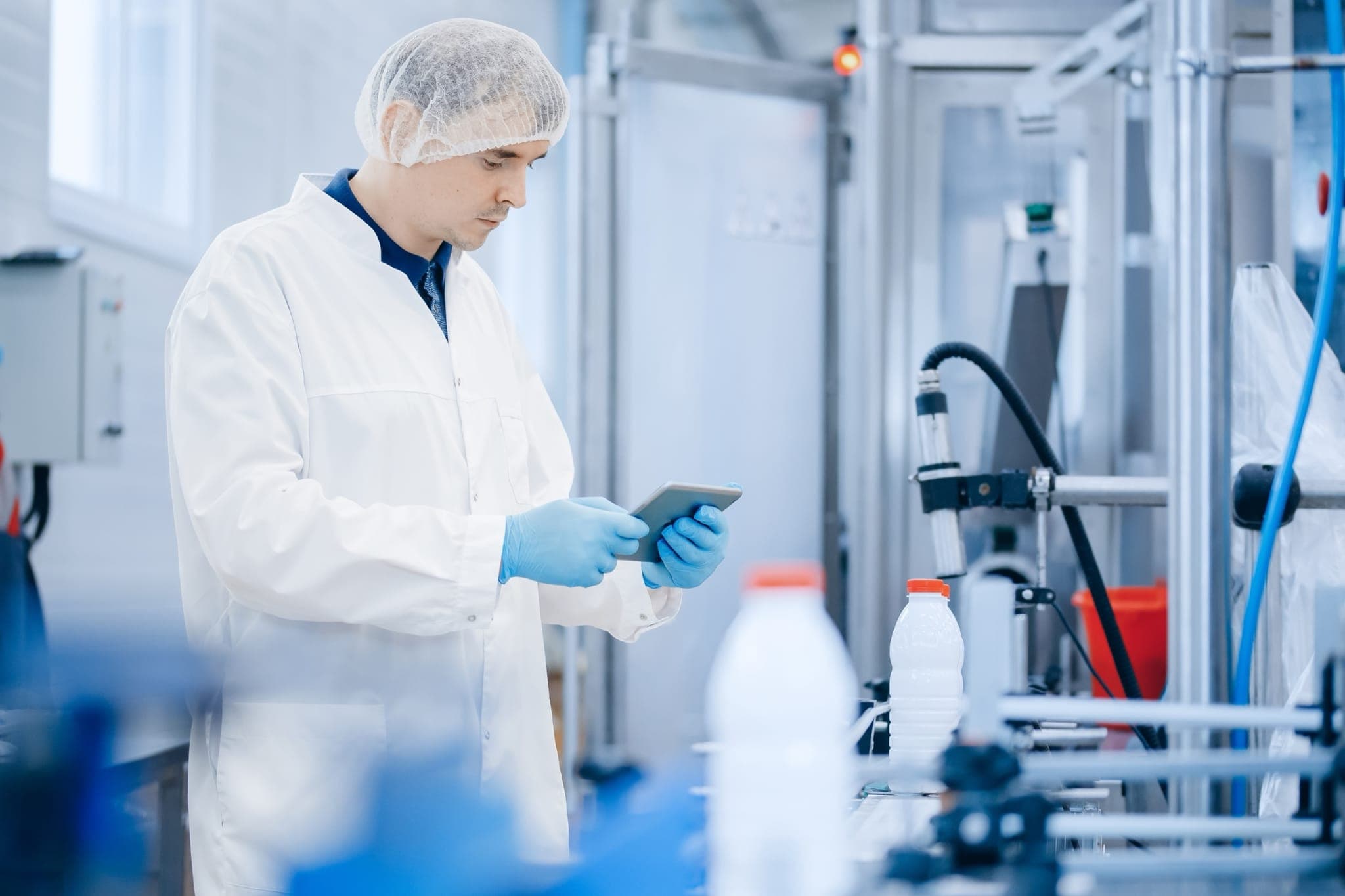 Dairy plant technician monitoring a bottle filling line on a tablet