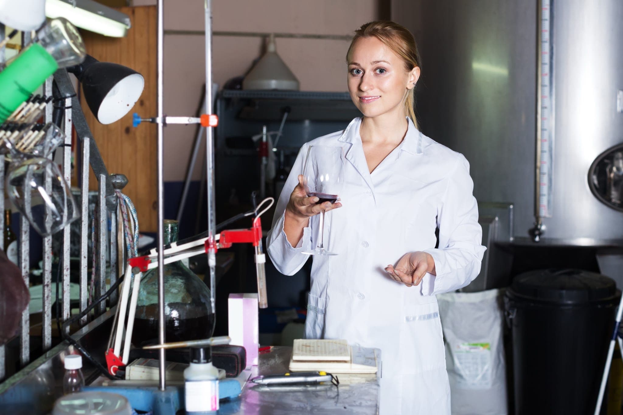 Oenologist evaluating red wine clarity in a stability testing laboratory