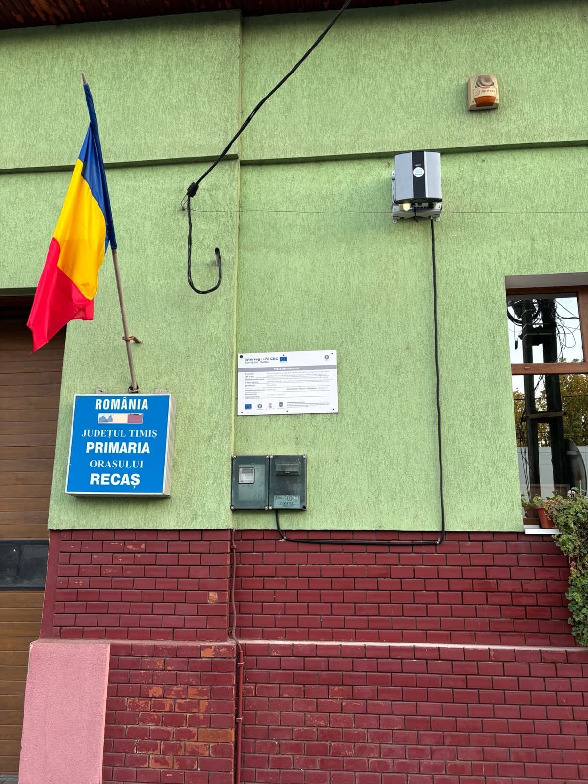 O stație Oizom Polludrone montată pe Primăria Orașului Recaș, lângă plăcuța proiectului „Blue Sky” finanțat de UE