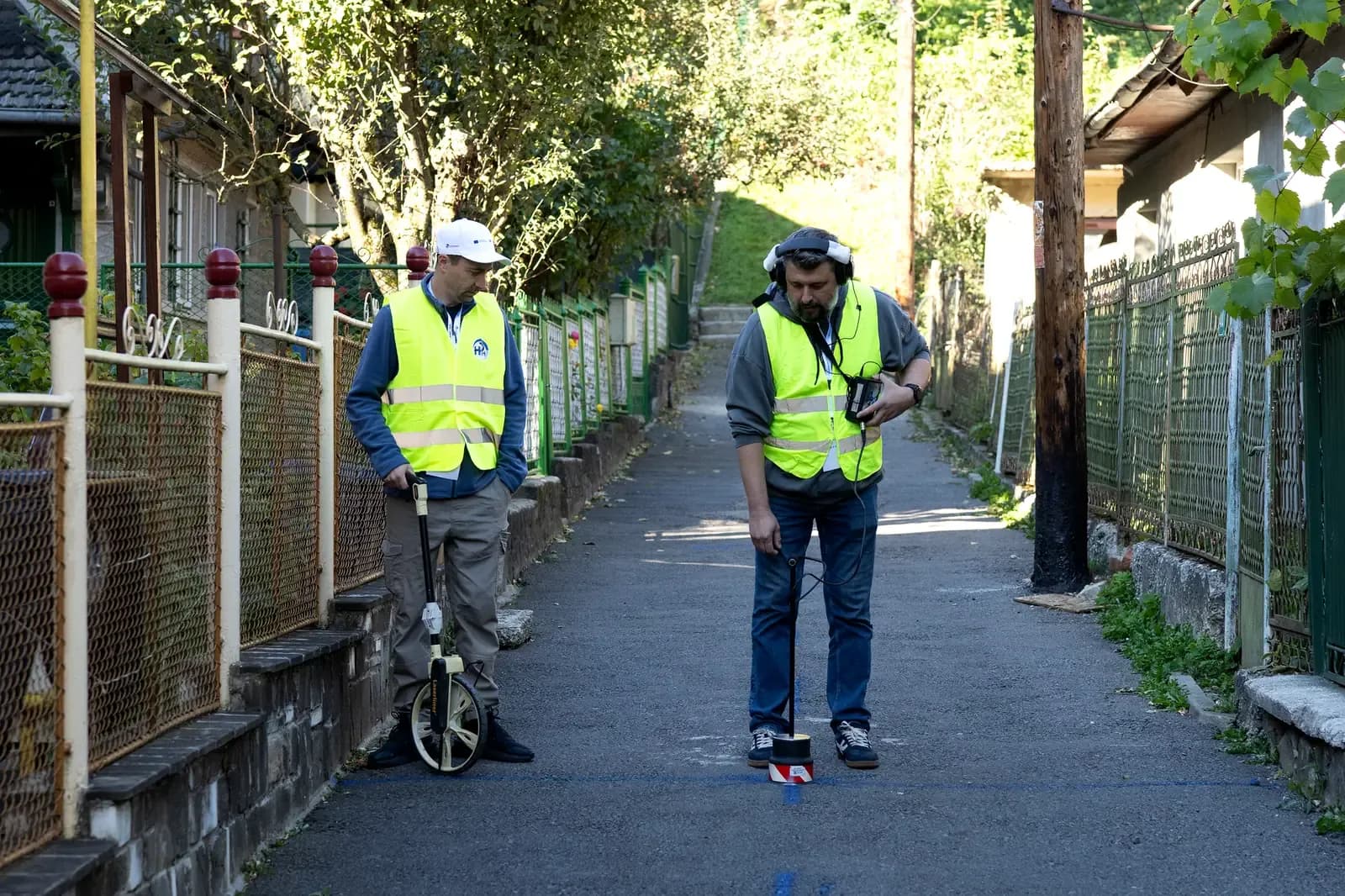 Operators walking a route in Sinaia with a measuring wheel and leak detection equipment