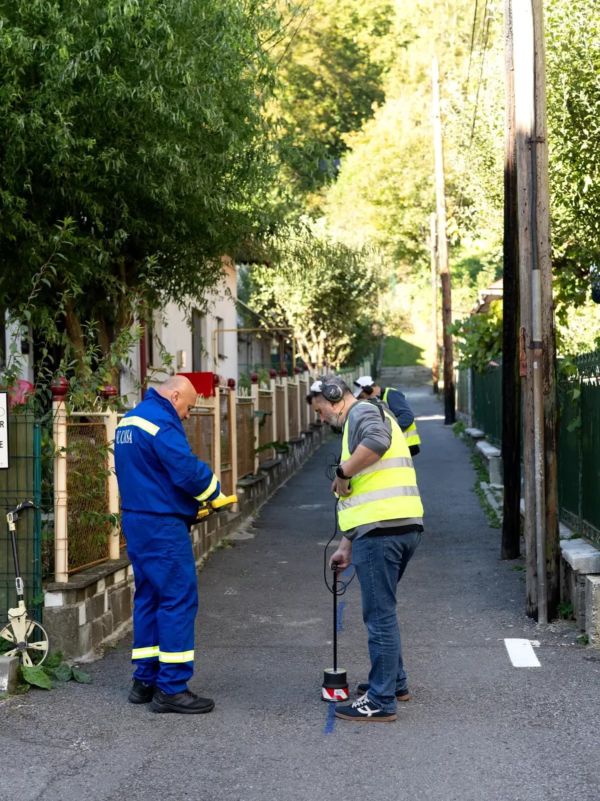 Listening for a leak on a narrow lane, with the route marked in blue on the asphalt