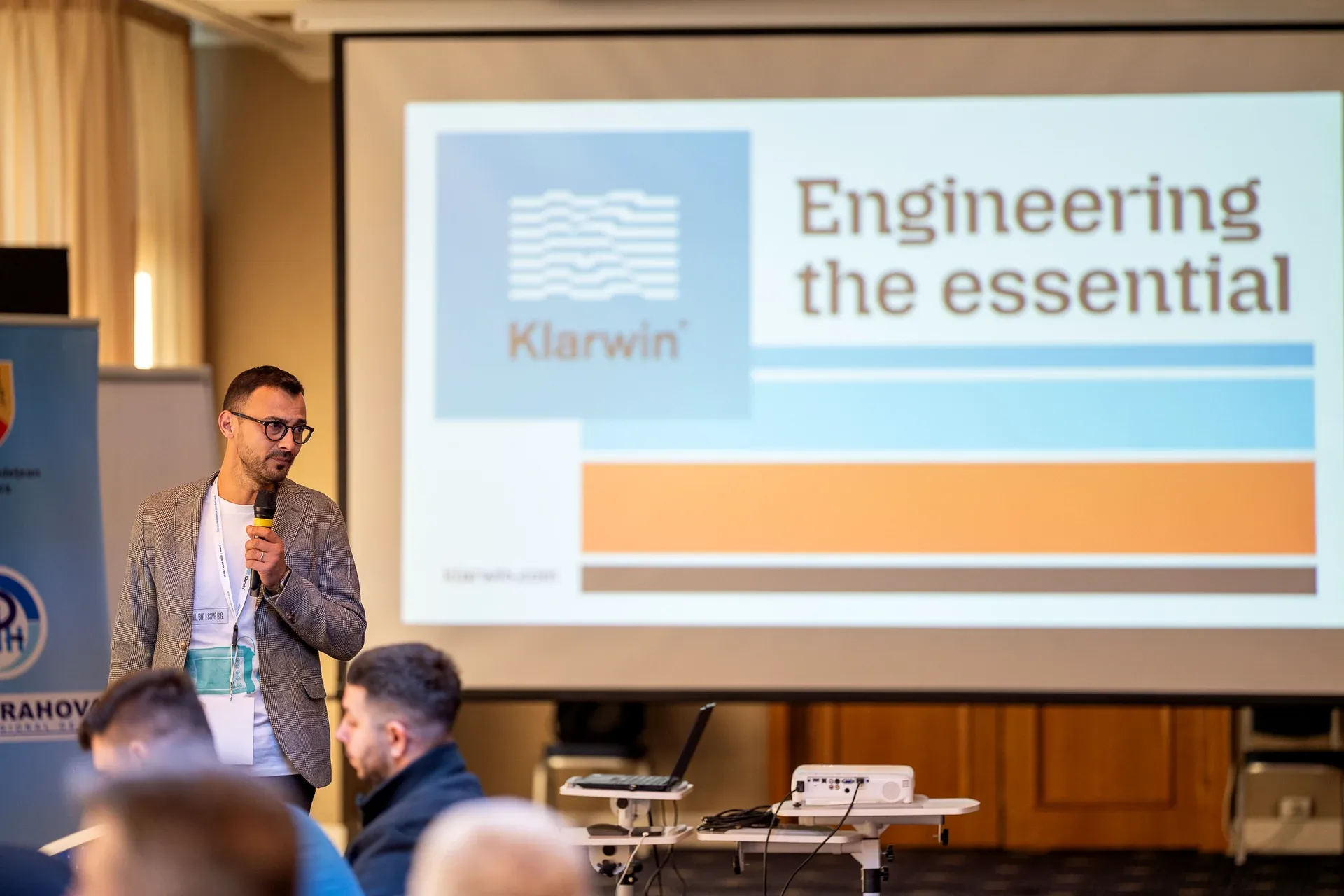 A speaker in front of the Klarwin® 'Engineering the essential' slide