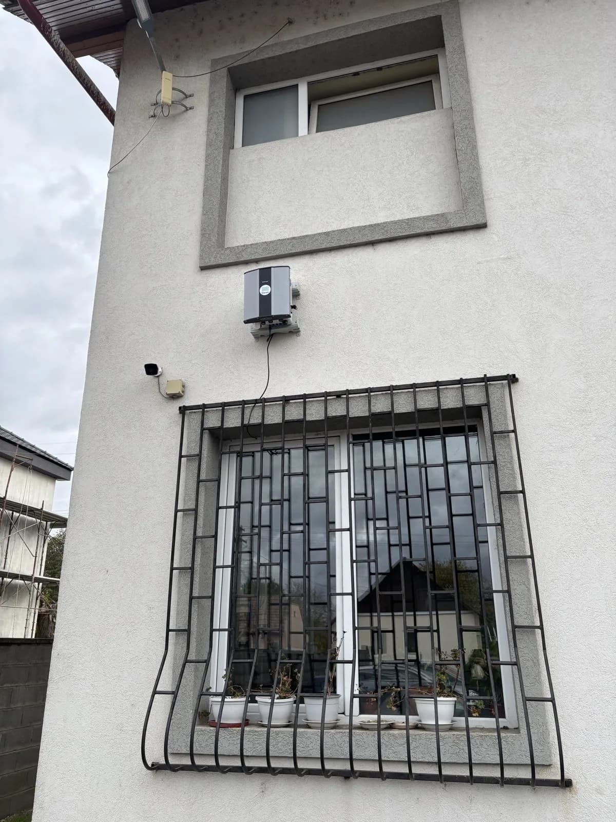 Stație Polludrone de calitate a aerului montată pe peretele unei clădiri, lângă o fereastră cu gratii